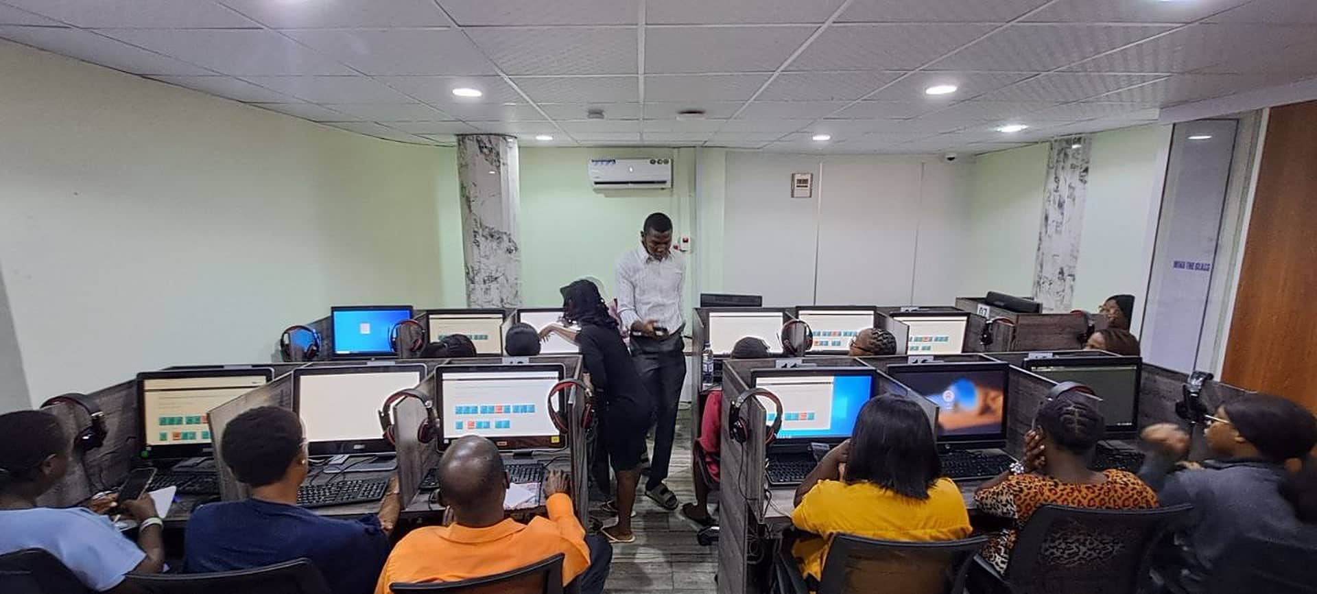 An instructor with learners at the computers in the Costech Academy IT lab