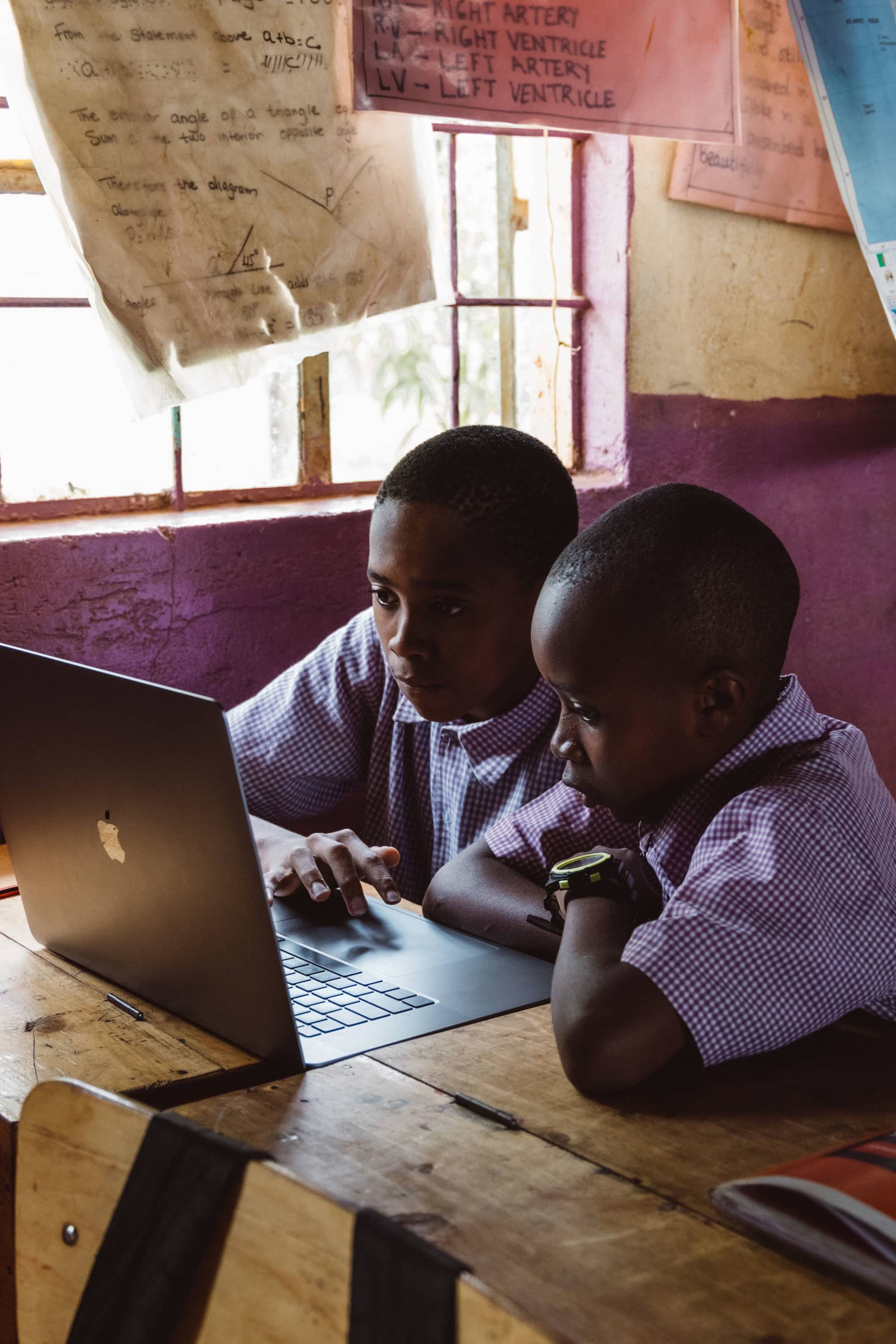 Two pupils in school uniform working on a laptop in their classroom