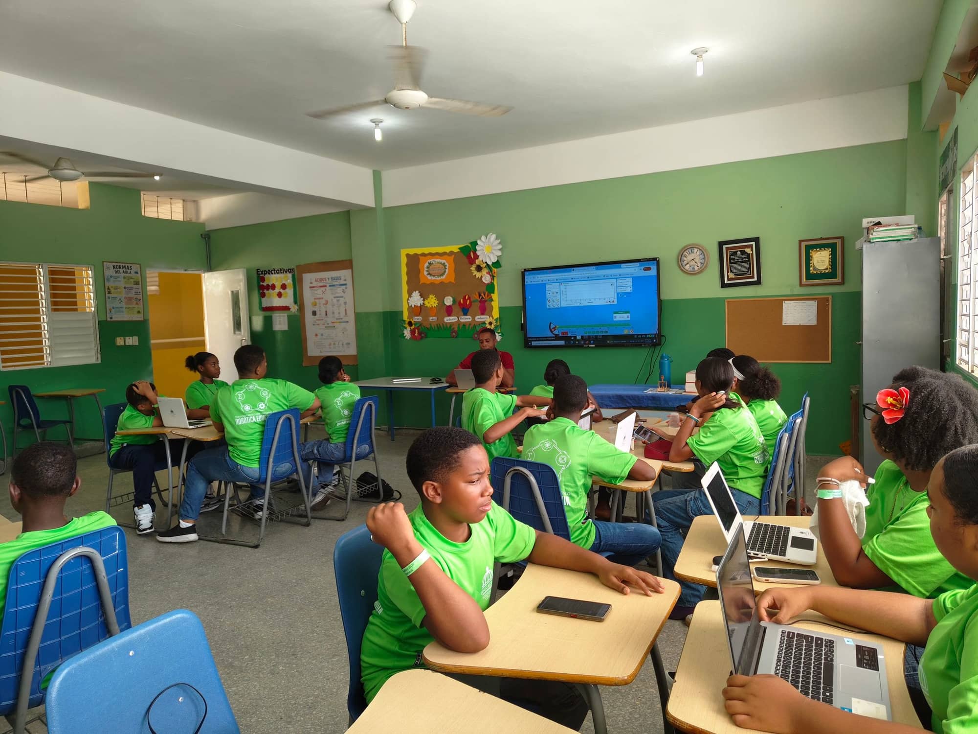 Pupils on laptops in a classroom with an interactive screen