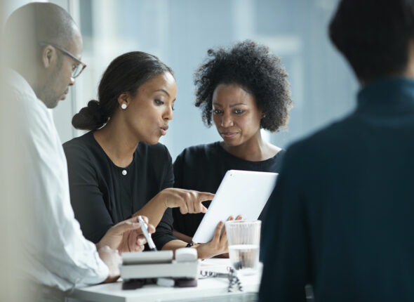 Group of co-workers standing around desk and having meeting